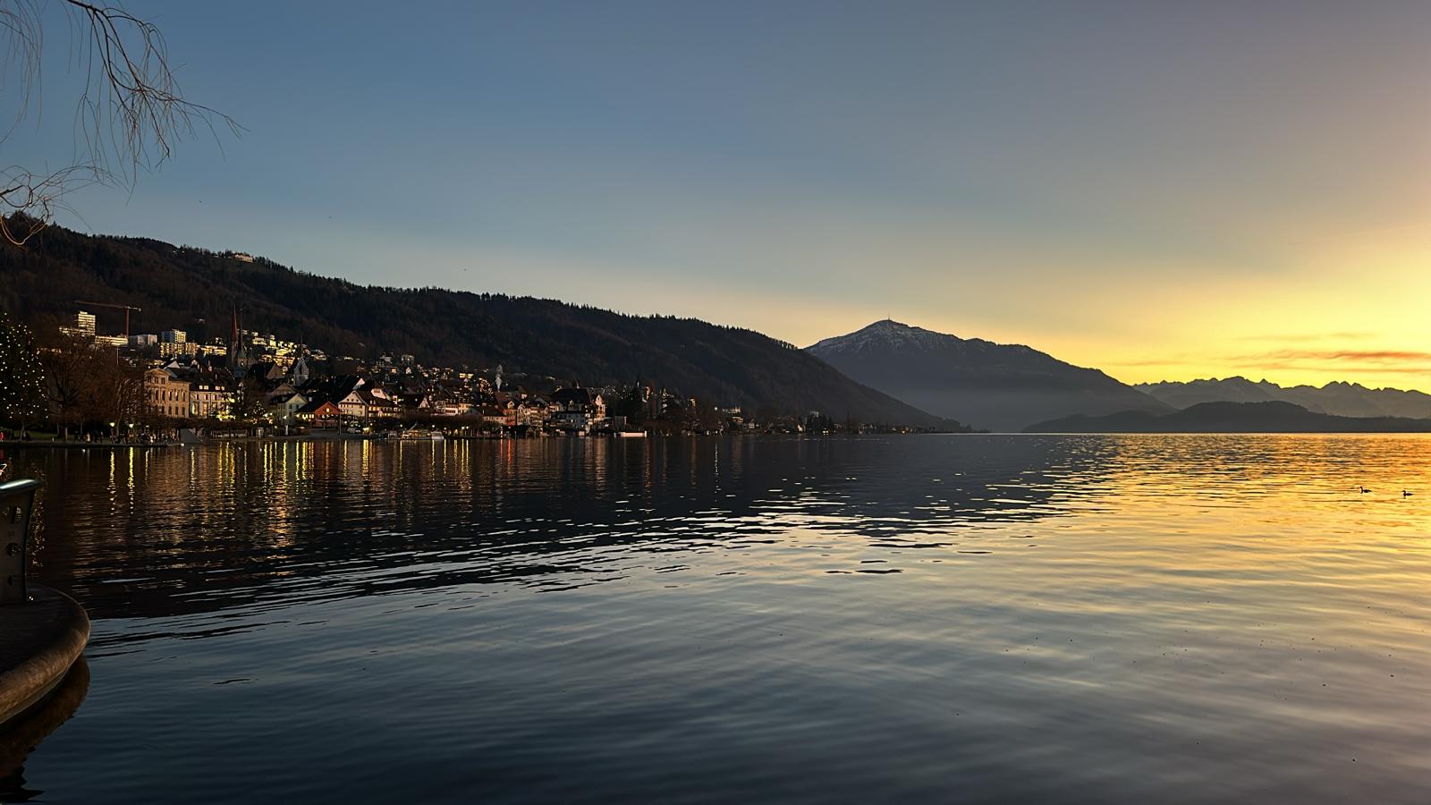 Old town of Zug at dusk, with the lake and the Bernese Alps in the distance